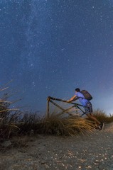 Person looking at the blue night sky with stars and galaxies