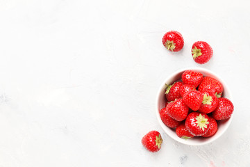 Ripe juicy strawberries in a bowl on a light background. Top view