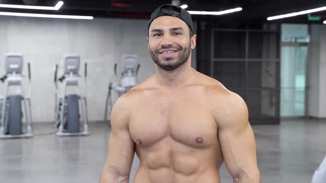 Cheerful muscular man moving his chest muscles in the gym.