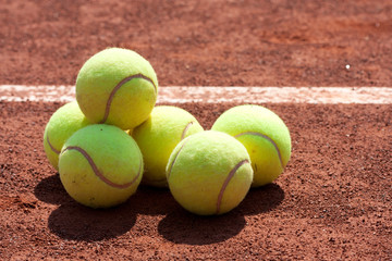 Close up of tennis balls on clay court.