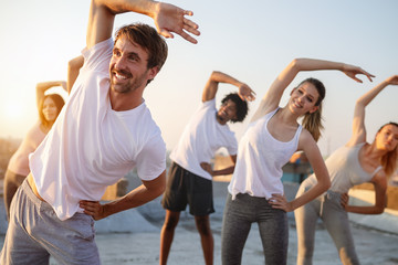 Group of athletic young people, friends in sportswear doing exercises. Sport outdoors