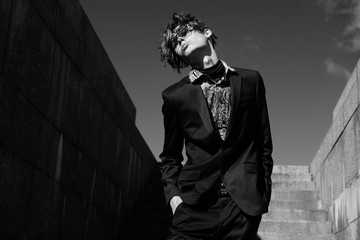 Portrait of sexy handsome fashion nale model dressed in elegant suit posing outdoor