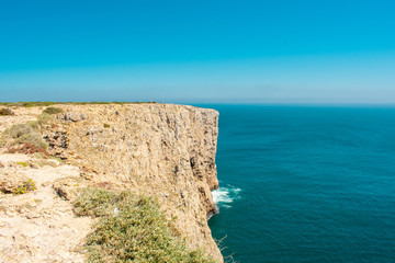 Cliffs on Coast of Atlantic Ocean in Sagres, Algarve Portugal. Horizon over water against blue sky.