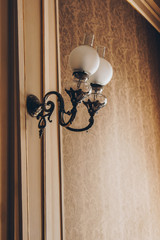Wall sconce on the wall with vintage beige wallpaper. interior room with luxury decorations and lamps