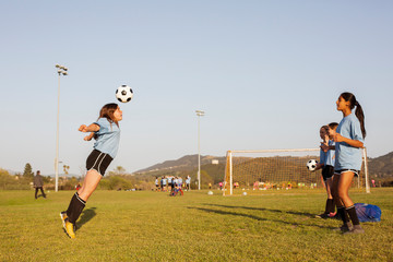 Fototapeta premium Girls practicing soccer in grassy field