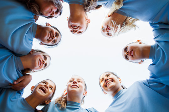 Low angle view of happy girls team huddling against clear sky