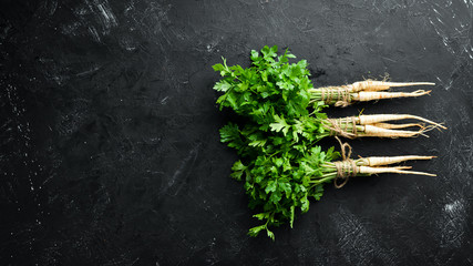 Obraz na płótnie Canvas Root parsley and parsley on a black background. Top view. Free space for your text.