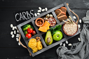 Foods high in carbohydrates: bread, pasta, avocado, flour, pumpkin, broccoli, beans, spinach. The concept of healthy eating. On a black background.