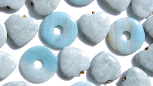 Semi-precious stone hearts and donuts of amazonite are rotating in a clockwise direction top view