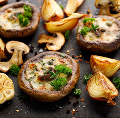 Baked portobello mushrooms stuffed with cheese and herbs on a black background, close-up. Vegetarian food
