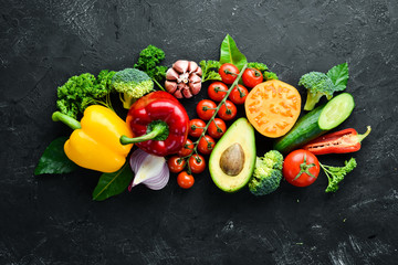 Fresh vegetables on a black background. Avocados, tomatoes, potatoes, paprika, citrus. Top view. Free space for your text.