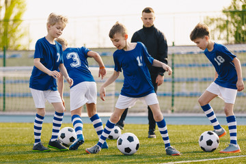 Obraz premium Football Soccer Training Drills: Young Players Practicing Soccer Run with Ball. Soccer Training on Fresh Grass Field