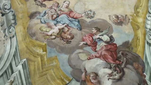 Angels in the clouds painted on the ceiling of catholic church. The inside of an antique Italian christian temple. Angels in the clouds painted. Close up view