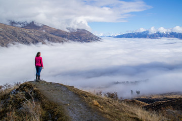 Fototapeta na wymiar Low clouds or fog (inversion) above lake Wakatipu and Queenstown valley. View of the scenic road and snow covered peaks of Single cone, Cecil Peak and Mount Nicholas. Panoramic landscape. New Zealand.