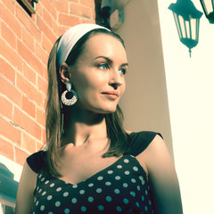 A girl in a polka dot dress by the brick wall. Retro style