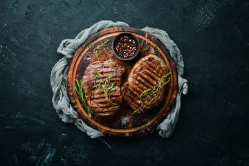  Grilled beef steak medium rare on a black stone table. Top view. Free space for your text. © Yaruniv-Studio