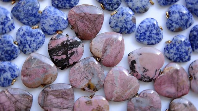 Semi-precious stone hearts and donuts of sodalite and rhodonite are rotating in a clockwise direction top view