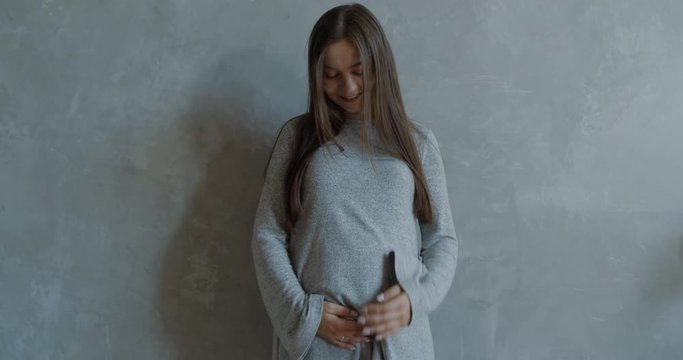 Happy caucasian pregnant women with big belly standing and rubbing her belly. 60 fps