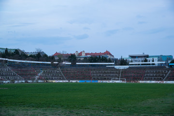 Fototapeta premium Abadoned Stadion Za Luzankami is a currently inactive stadium in Brno, Czech Republic. Captured in spring sunset, sky and clouds was colored to blue dark colors. Photo from tribunes and inside middle