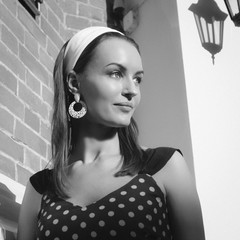 A girl in a polka dot dress by the brick wall. Retro style