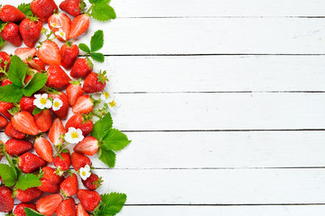 Strawberry with leaves on a white wooden background. Berries Top view. Free space for your text.