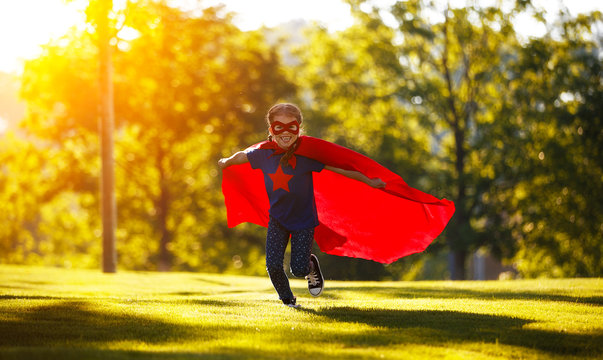 concept happy child superhero hero in red cloak  in nature