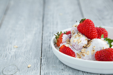 juicy fresh strawberries drenched in yogurt and oatmeal on a gray wooden background. Healthy breakfast.