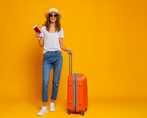 concept of travel. happy woman girl with suitcase and  passport on  yellow background.