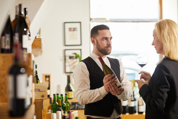 Waist up portrait of professional sommelier choosing wine for client in restaurant, copy space