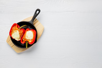 Bell pepper stuffed with meat with melted cheese mozzarella on top baked in oven in cast iron skillet. Top view. Natural wooden background.