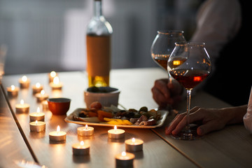 Fototapeta na wymiar Closeup of romantic dinner with wine glasses and snacks on wooden table lit by candle light, copy space