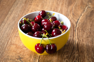 Fresh organic sweet cherries in a glass bowl on wooden table