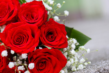 A bouquet of red roses with tiny white flowers and green leaves