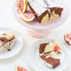 Slices of vanilla and chocolate marble cake on white background. Brunch style dessert. Fresh homemade pastry with juicy fig fruit. Pink plate for desserts.