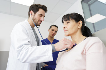 male doctor measuring blood pressure of woman in hospital