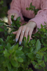 Fototapeta na wymiar hand on green leaves, girl with blue manicure, silver rings, infinity ring.