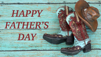 cowboy boots and hat laying on a teal wood background with happy fathers day in brown text