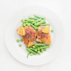 Сlose up of juicy grilled chicken with green beans and orange. Healthy green vegetable lunch with meat, top view on white background. 