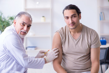 Obraz na płótnie Canvas Male patient visitng doctor for shot inoculation 