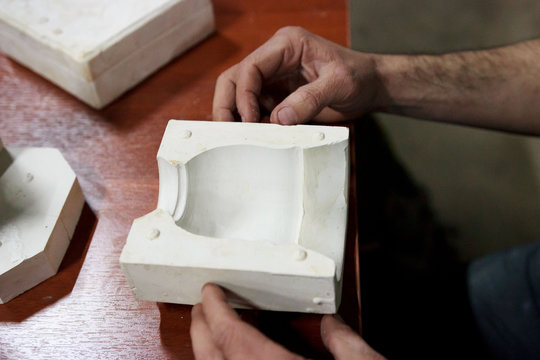 meeting potters. training courses for novice ceramists. the master potter with 15 years of experience shows a gypsum plaster mold for making many ceramic cups. reportage.