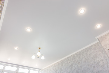 Stretch ceiling in the room with a chandelier and spotlights