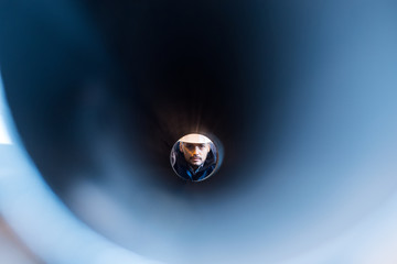 man looking through a pipe