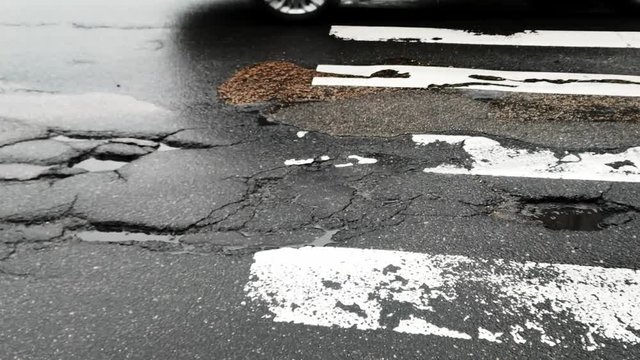 Cracked ruined asphalt pit roads pedestrian walkway, panning shot