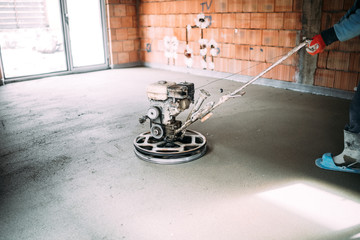 Construction industrial worker finishes concrete screed with trowel machine