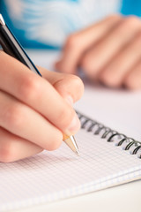 Man's hand with a black-gold pen over a clean sheet of checkered notebook