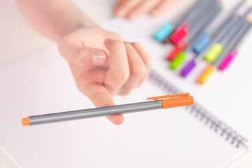 Orange felt-tip pen in balance on a child's finger.