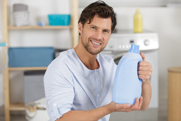 smiling young man holding laundry detergent