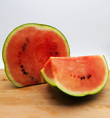 Fresh ripe striped sliced watermelon on wooden table, white background