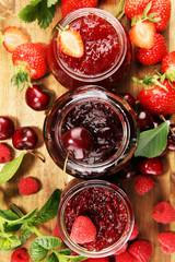 assortment of jams, seasonal berries, cherry, mint and fruits in glass jar