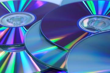 Płyty dvd, cd, i blu-ray z odbitymi, kolorowymi smugami światła.